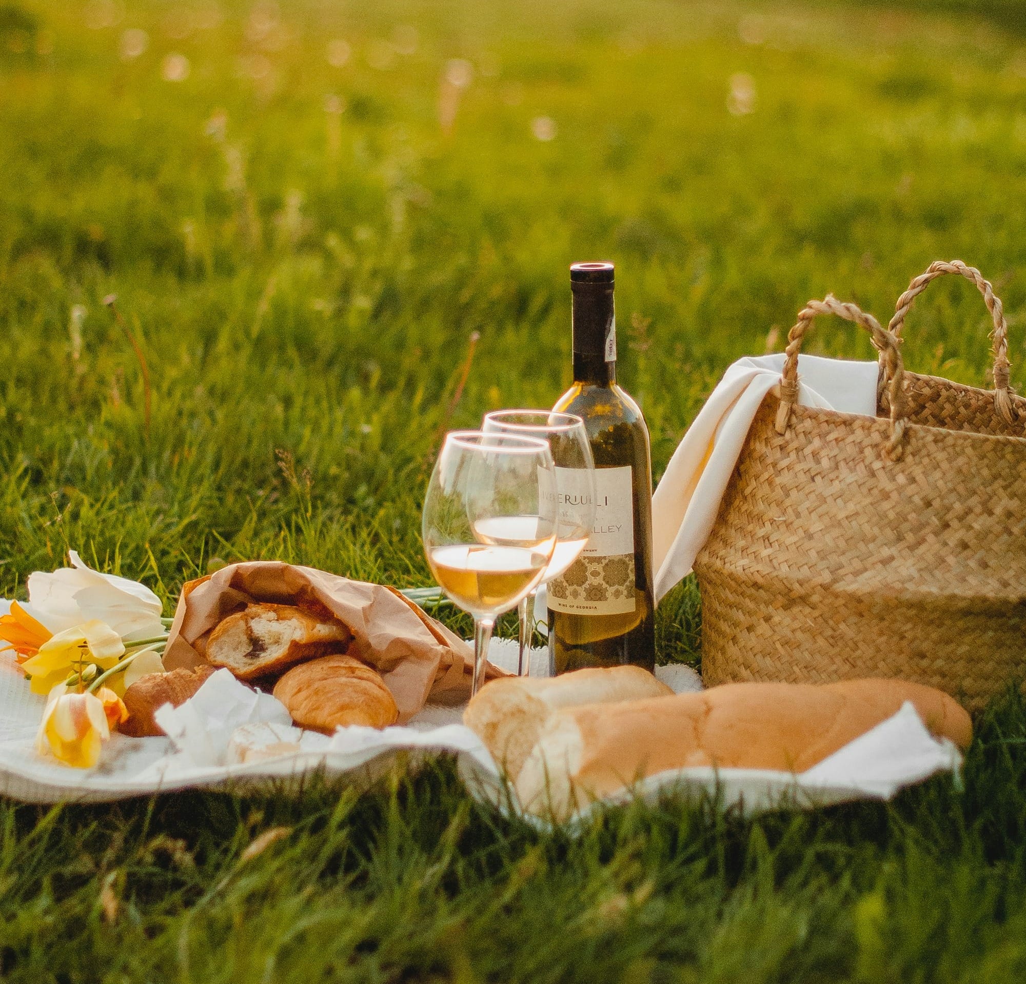 clear glass bottle beside brown wicker basket on green grass during daytime